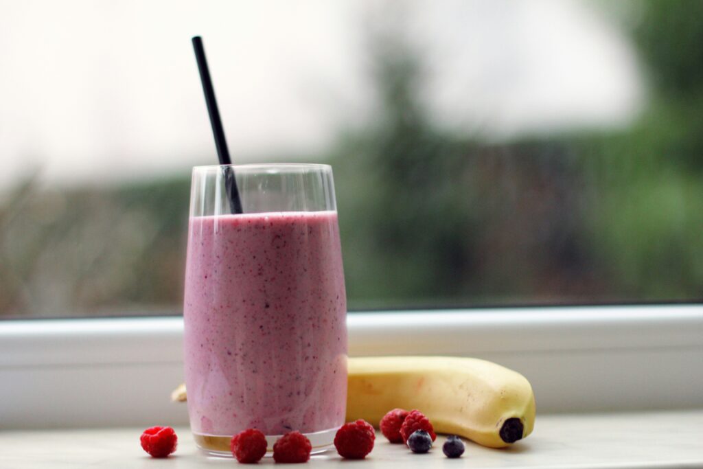 A berry and banana smoothie in a glass with a straw