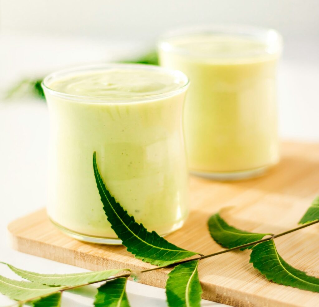 Two yellow smoothies with a green twig