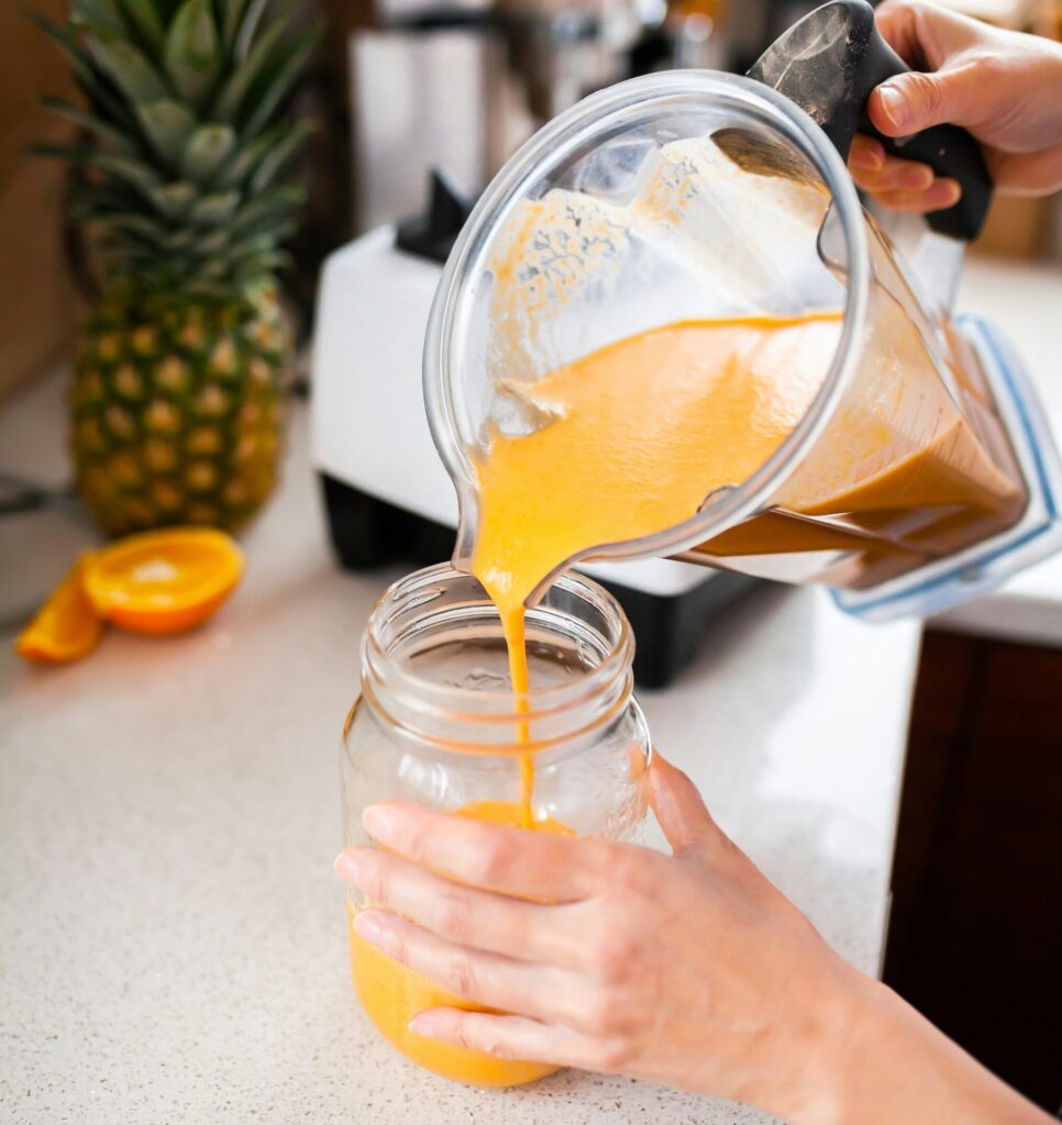 Pouring smoothie out of a jug into a glass jar