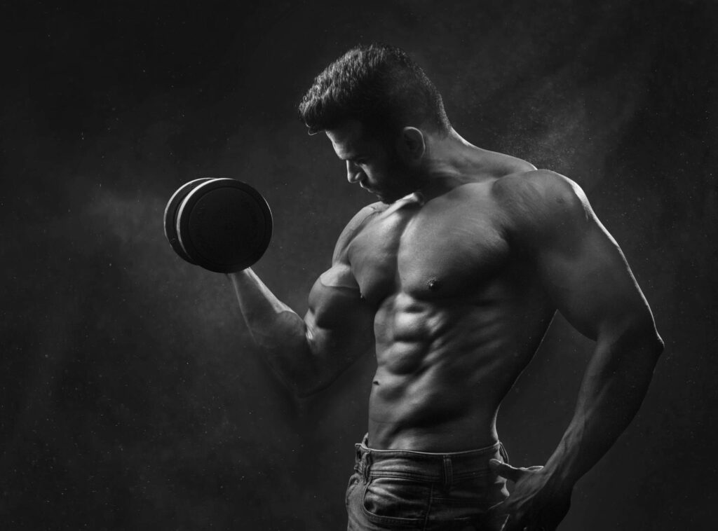 A man doing a dumbbell curl showing his physique