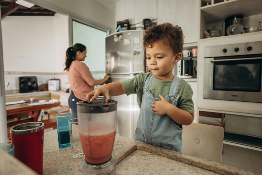 A kid with a smoothie jug in the kitchen
