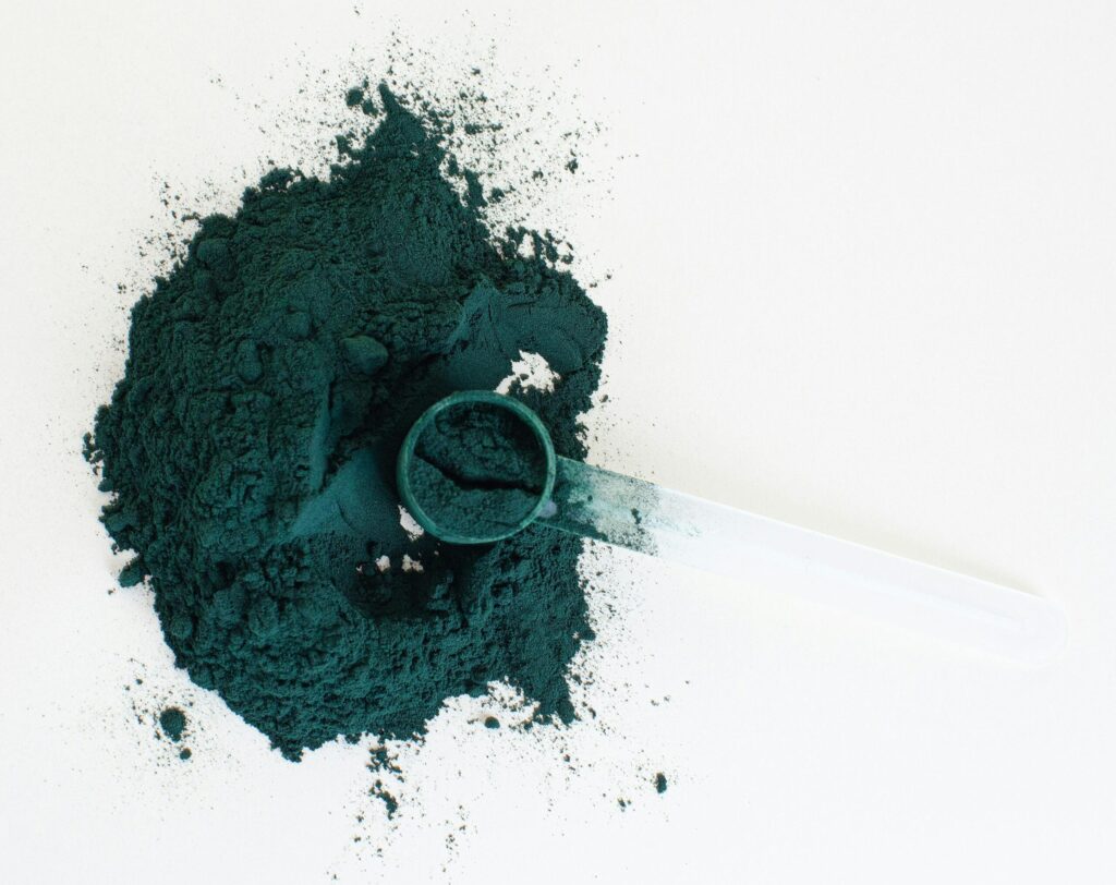 Spirulina powder in scoop and on table