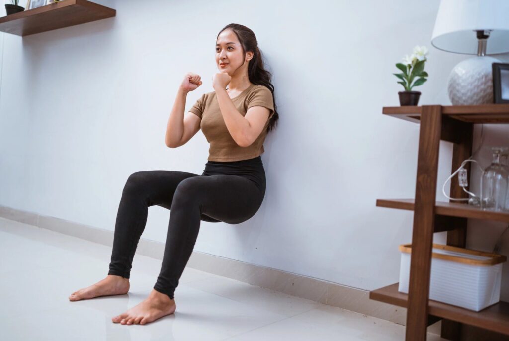 Woman doing wall squats to boost metabolism