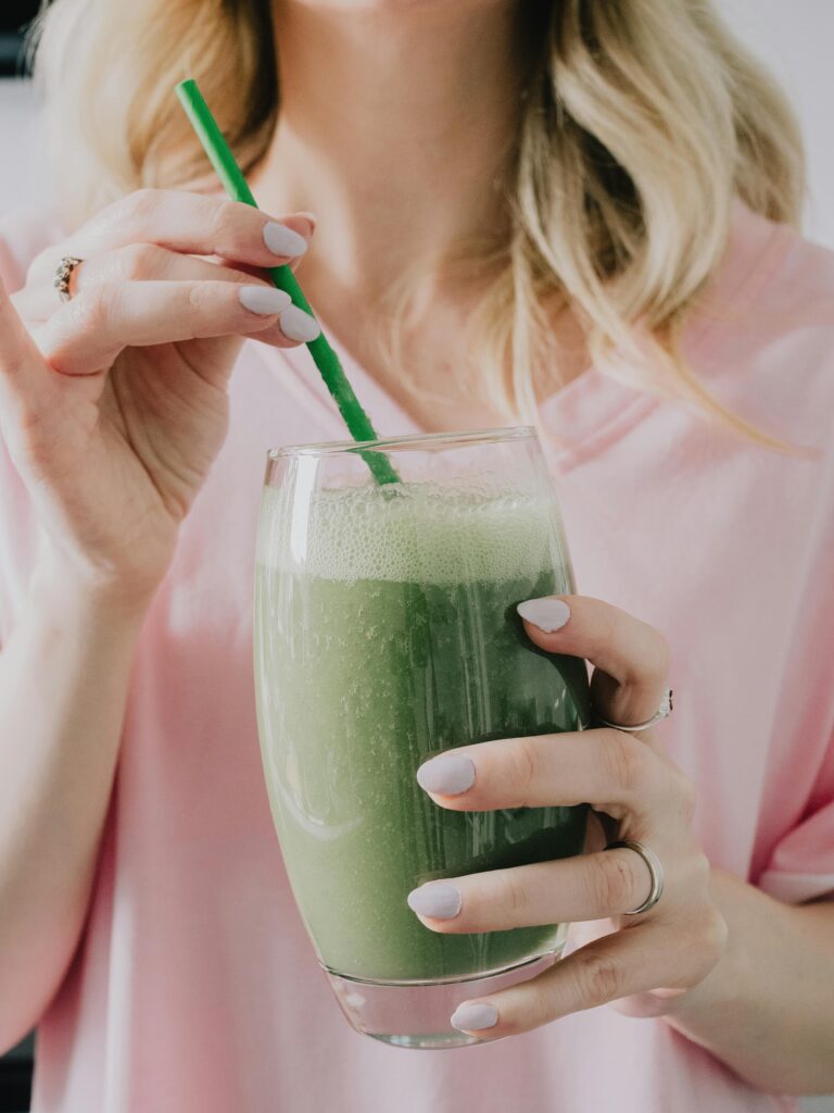 a woman holding a green smoothie for How to look leaner after 30