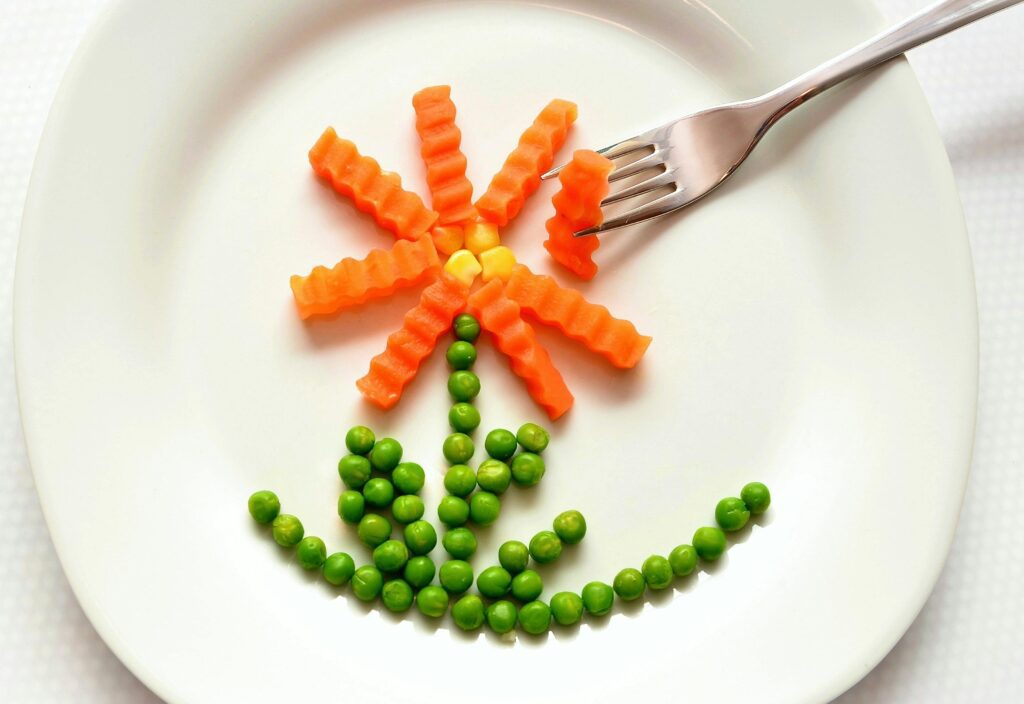 A plate with carrots and peas on